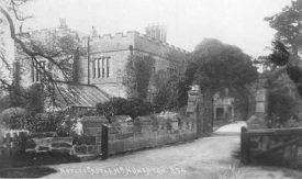Stone archway entrance to Astley Castle. Part of castle and greenhouse roof. 1900s. | Warwickshire County Record Office reference CR352/11/7