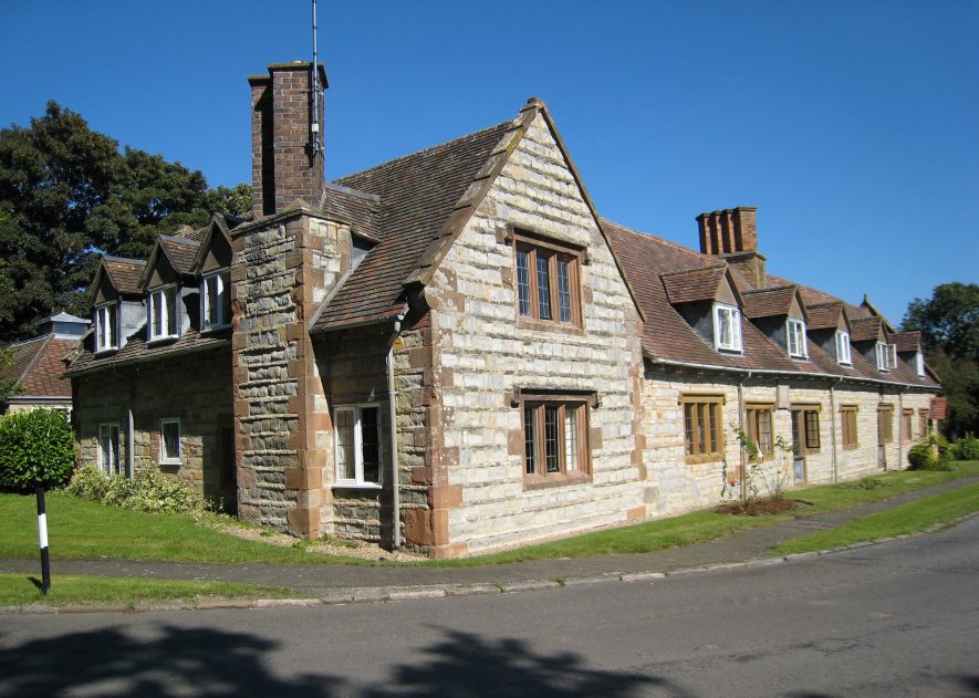 A pale limestone building with red sandstone dressings; two stories with gabled dormer windows in the tiled roof upstairs | Image courtesy of Anne Langley