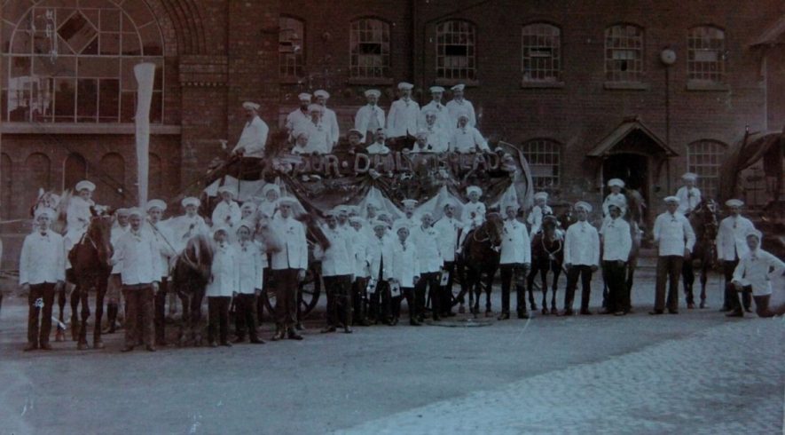 Bakers' entry in the Coventry Carnival 1907. Taken outside Robbins and Powers Flour Mills in Wheatley Street which shows how many bakers there were in the city at that time! The large white mark on the left hand side of the photograph is a bag which was held up to bedroom windows to collect cash! The display on the side of cart says ‘Your Daily Bread’ made from bread. Little Alf is the 3rd boy on the right from the bag. | Image supplied by Doris Pails.