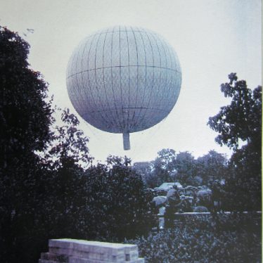 Balloon rising over crowd of people with umbrellas. Garden with trees and stack of bricks in foreground | Courtesy of Warwickshire County Council, Leamington Library Local Studies Collection (Windows on Warwickshire website), reference T 394.25.9 6084