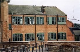 3-storey brick building with large green-painted windows (some broken and some boarded up) | Anne Langley