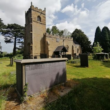Parish church in background with yew trees on either side; gravestone in the foreground. | Image courtesy of Andrew Carruthers