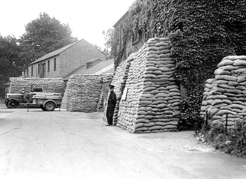 Auxiliary Fire Station (sand-bagged entrance) with fire engine at Leamington Spa. Kell (Jack) Bubb on left, Vic Godfrey on right.  1940s |  IMAGE LOCATION: (Warwickshire County Record Office) PEOPLE IN PHOTO: Godfrey, Vic, Godfrey as a surname, Bubb, Kell also known as Jack, Bubb as a surname