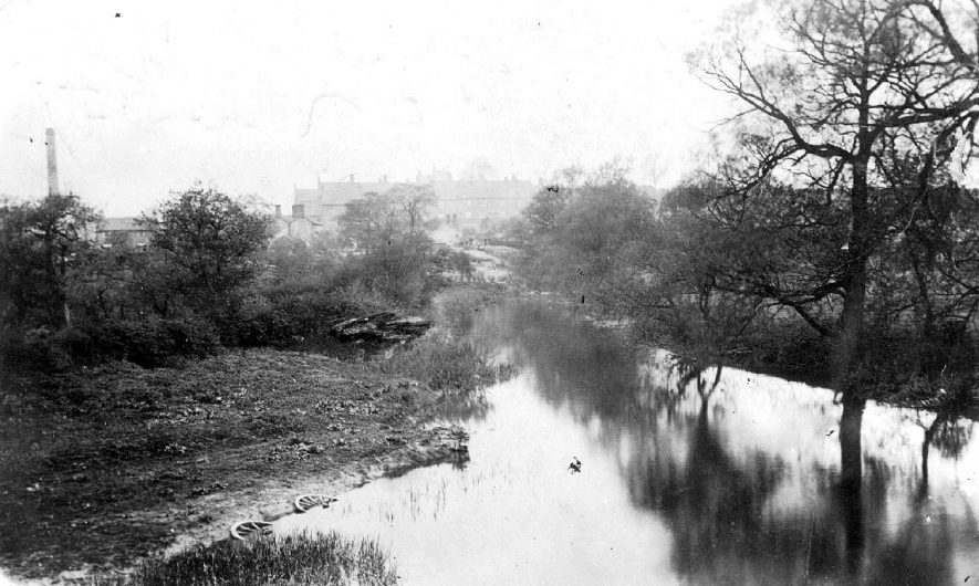 The River Anker at Polesworth, with the old brick works on the left. Note the two cart wheels half submerged in the foreground.  1910s |  IMAGE LOCATION: (Warwickshire County Record Office)