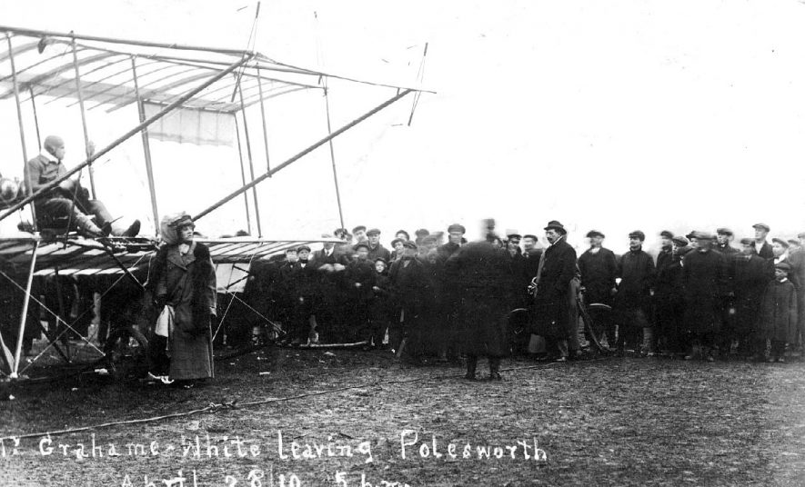 Photograph bears the inscription: Mr Grahame White leaving Polesworth, April 28th 1910 at 5 p.m.  It shows the incredible flying machine he flew, and a large number of interested onlookers |  IMAGE LOCATION: (Warwickshire County Record Office) PEOPLE IN PHOTO: White, Grahame, White as a surname