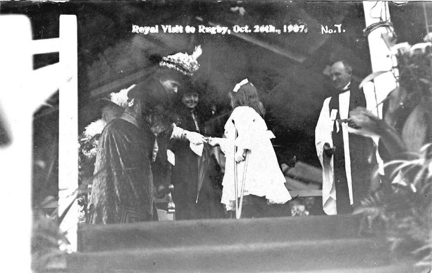 Crippled girl on podium with royal lady, another lady and a clergyman at the royal visit to Rugby.  1907 |  IMAGE LOCATION: (Warwickshire County Record Office)