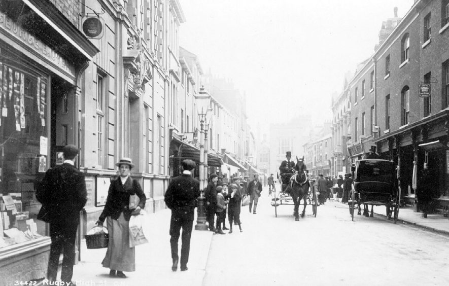 High Street, Rugby, showing horse drawn vehicles including a cab and pedestrians.  Near left of photograph is George E. Over, stationers and printers. photo no. The Photochrom Co. Ltd. 34422.  1900s |  IMAGE LOCATION: (Warwickshire County Record Office)