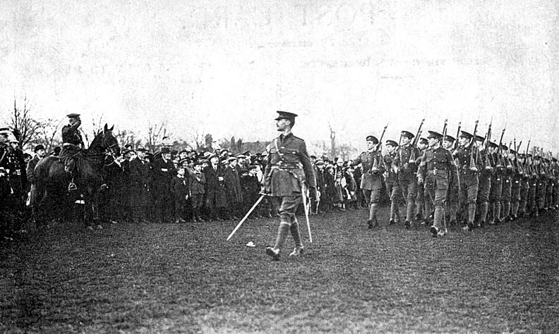 Rugby School O.T.C. saluting the flag at Rugby's celebration of The Armistice, 1918. [The Rugby School Officer Training Corps, led by its Band, headed the main procession through the town on November 12th. The procession started and finished at the Recreation Ground. The flag was saluted on the return to the Recreation Ground.] |  IMAGE LOCATION: (Warwickshire County Record Office)