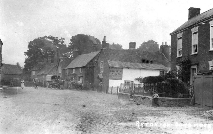 Part of village street with cottages, The Blacksmith's Arms and two storey brick house, Ryton on Dunsmore. Horse with covered cart. Children.  1900s | IMAGE LOCATION: (Warwickshire County Record Office)