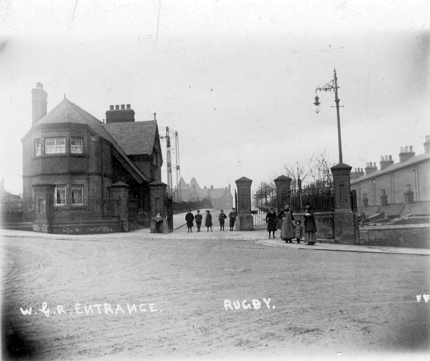 Factory gates of Willans & Robinson, Rugby, on the right is the Old Station Square (the site of the original railway station).  1900s |  IMAGE LOCATION: (Warwickshire County Record Office)