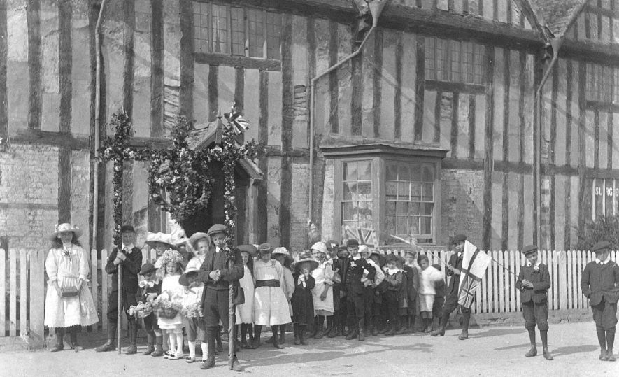Long Itchington showing a group of children dressed for May Day and carrying garlands and flags They are standing outside the Tudor House.  1910s |  IMAGE LOCATION: (Warwickshire County Record Office)
