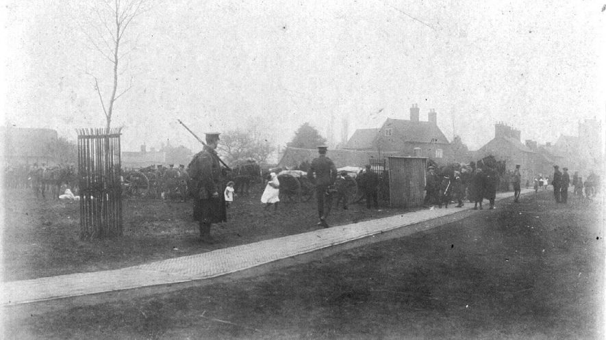 Group of Royal Artillery with guns and gun-carriage, an armed sentry with children looking on, Long Itchington.  1914-18 |  IMAGE LOCATION: (Warwickshire County Record Office) IMAGE DATE: (1914 -1918)
