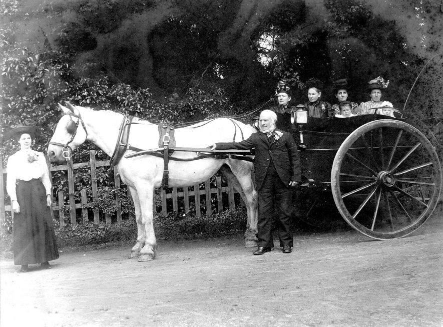 Mr. George Hartley Dabbs standing alongside a pony and trap in which women and children are seated.  Another woman is standing in front of the horse. Coleshill.  1910s |  IMAGE LOCATION: (Coleshill Library) PEOPLE IN PHOTO: Dabbs, George Hartley, Dabbs as a surname