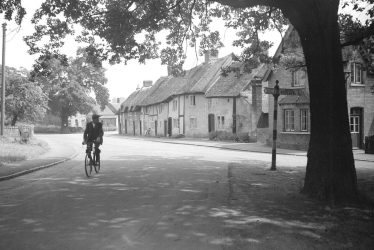 Monks Kirby.  Cyclist making his way through the village