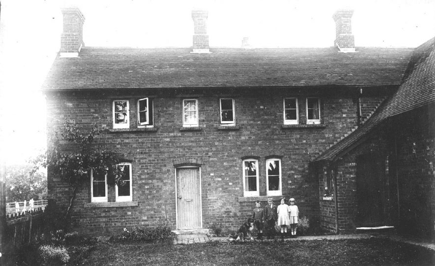 Two boys and two girls with their dog standing outside a house in Hunningham.  1920s |  IMAGE LOCATION: (Warwickshire Museums. Photographic Collections.)