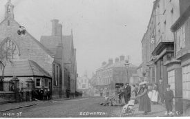 Bedworth, High Street. The building on the left is the Bedworth Central C of E school . Lady with a push chair. 1900s[The school has since been demolished to make way for a new health centre] |  IMAGE LOCATION: (Warwickshire County Record Office)