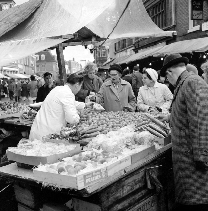 People crowding round Clarke's fruit and vegetable stall at Nuneaton's market.  December 31st 1966 |  IMAGE LOCATION: (Warwickshire County Record Office)