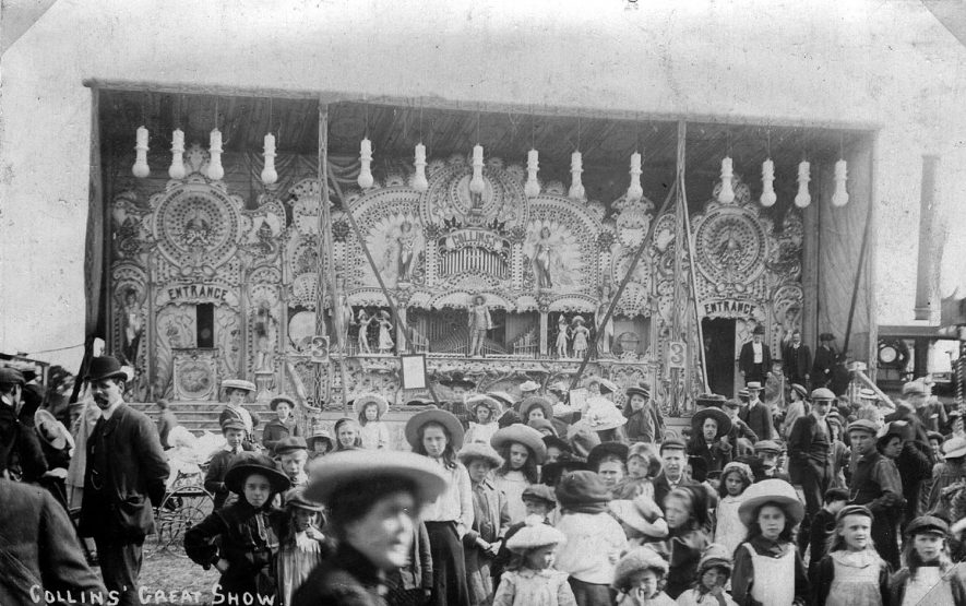 Collins' Great fairground show, with a large group of people in front. Leamington Spa.  1900s |  IMAGE LOCATION: (Leamington Library)