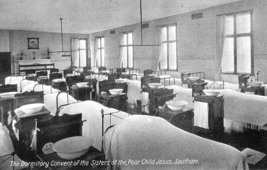 'The Dormitory, Convent of the Sisters of the Poor Child Jesus', shows rows of beds and tables with washing bowls and towels.  1910 |  IMAGE LOCATION: (Warwickshire County Record Office)