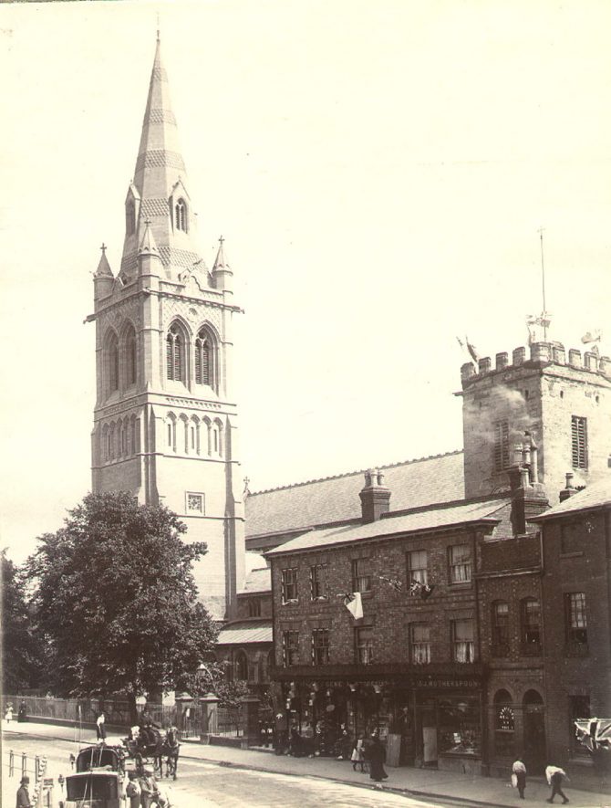 St Andrew's spire viewed from Church Street, Rugby.  General Stores and Wotherspoon' shops at right.  Carriages and pedestrians.  Flag indicates probable date of 1897, Queen Victoria's Jubilee.  1897 |  IMAGE LOCATION: (Rugby Library) SCAN DATE: (1?11/99)