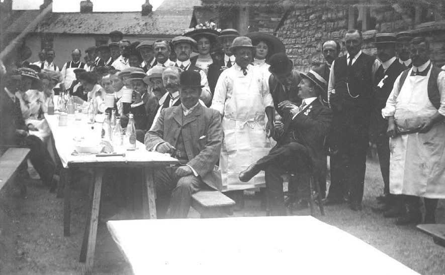 Group of adults around a trestle table enjoying a drink.  1900s |  IMAGE LOCATION: (Warwickshire County Record Office)