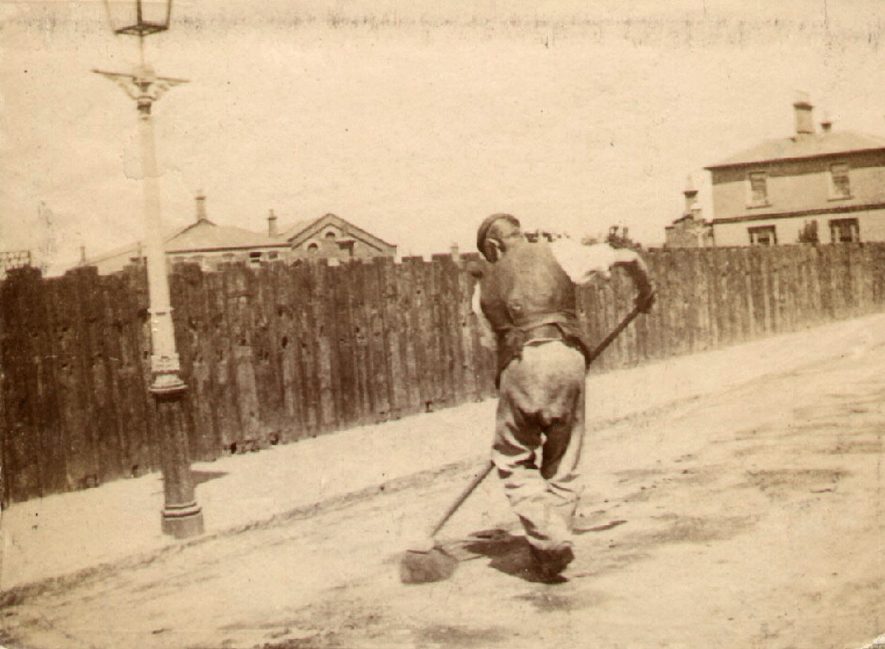 Man sweeping the road. Railway Terrace, Rugby, which was laid out as a private road by the Railway Company and lined with sleepers in 1840.  Plans for Railway Villas [one of which can be seen on the right] were passed in 1852.  This photograph was therefore taken after 1852. |  IMAGE LOCATION: (Rugby Library)