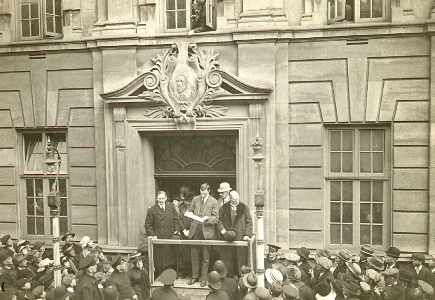 Rugby General Election, December 27th 1918. The result being announced from Benn Buildings by the Deputy Returning Officer, H M Blenkinsop Esq. Major Sir John Baird, the successful candidate is on the left of the photograph.Photograph supplied by kind permission of the Rugby Advertiser. |  IMAGE LOCATION: (Rugby Library) PEOPLE IN PHOTO: Blenkinsop, H M, Blenkinsop as a surname, Baird, Major Sir John, Baird as a surname