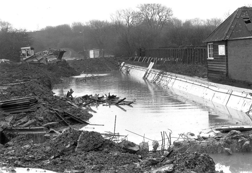 Council workmen demolishing the Avon Mill swimming pool and restoring the land, for use as a car parking extension of the council's depot at Hunters Lane, Rugby.  1977 |  IMAGE LOCATION: (Rugby Library)