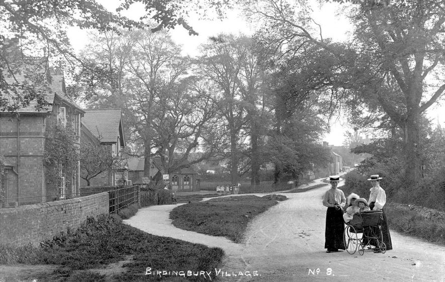 A street scene showing two ladies with a pram and two children, Birdingbury.  1900s |  IMAGE LOCATION: (Warwickshire County Record Office)