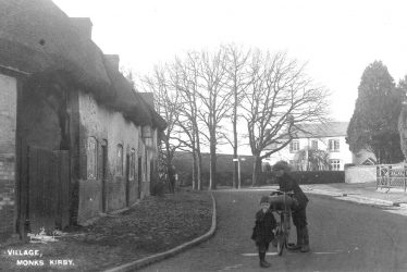 Monks Kirby.  Man and child standing in the road