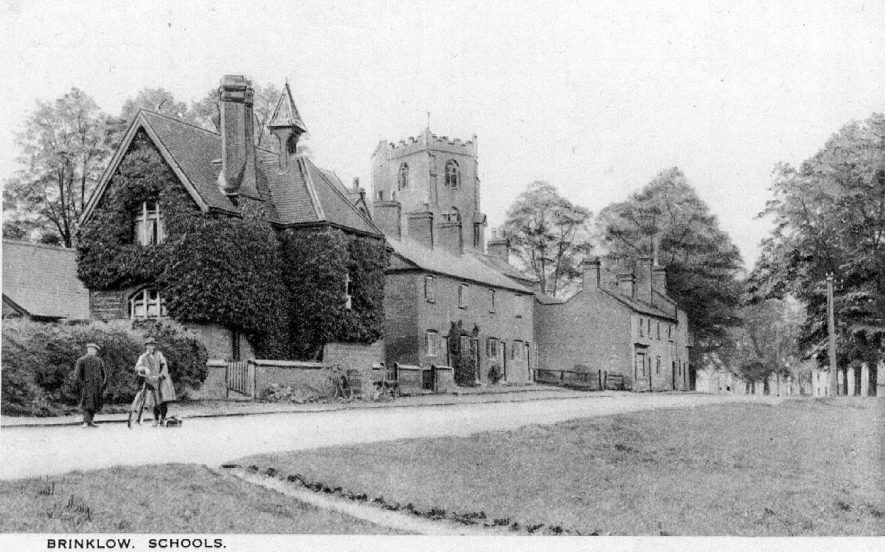 A street in Brinklow, showing school buildings, cottages, church tower, men and bicycles.  1920s |  IMAGE LOCATION: (Warwickshire County Record Office)