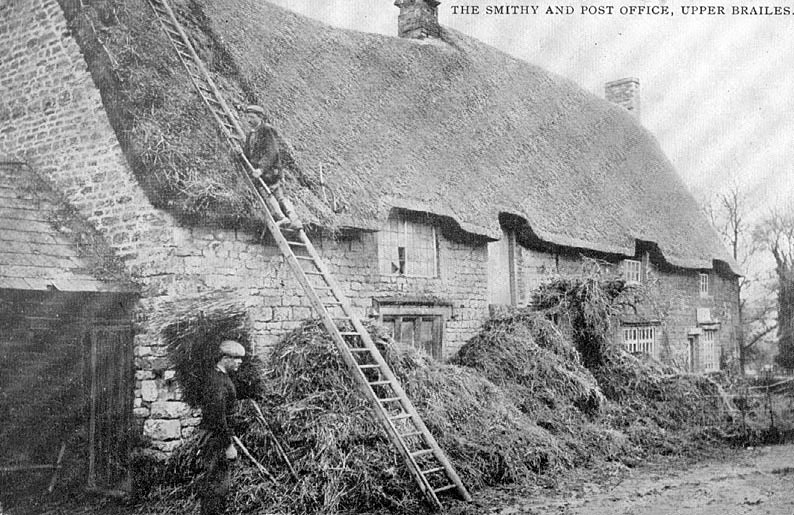 The Smithy and Post Office showing thatchers at work renewing the thatch.  1910s |  IMAGE LOCATION: (Warwickshire County Record Office)
