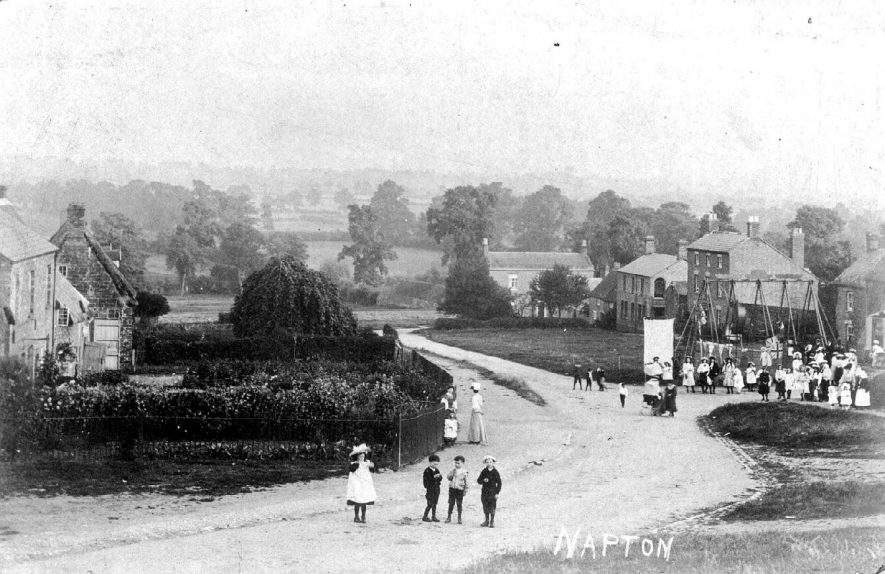 The Green, showing children at 'Napton Feast' (on back of pc. 'This is Napton Feast, a village holiday in August'); various children grouped around swings, others in the foreground.  1900s |  IMAGE LOCATION: (Warwickshire County Record Office)
