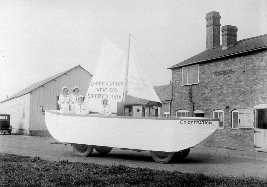 A carnival float in the form of a sailing boat from Alcester Co-operative Society. On the sail is printed  