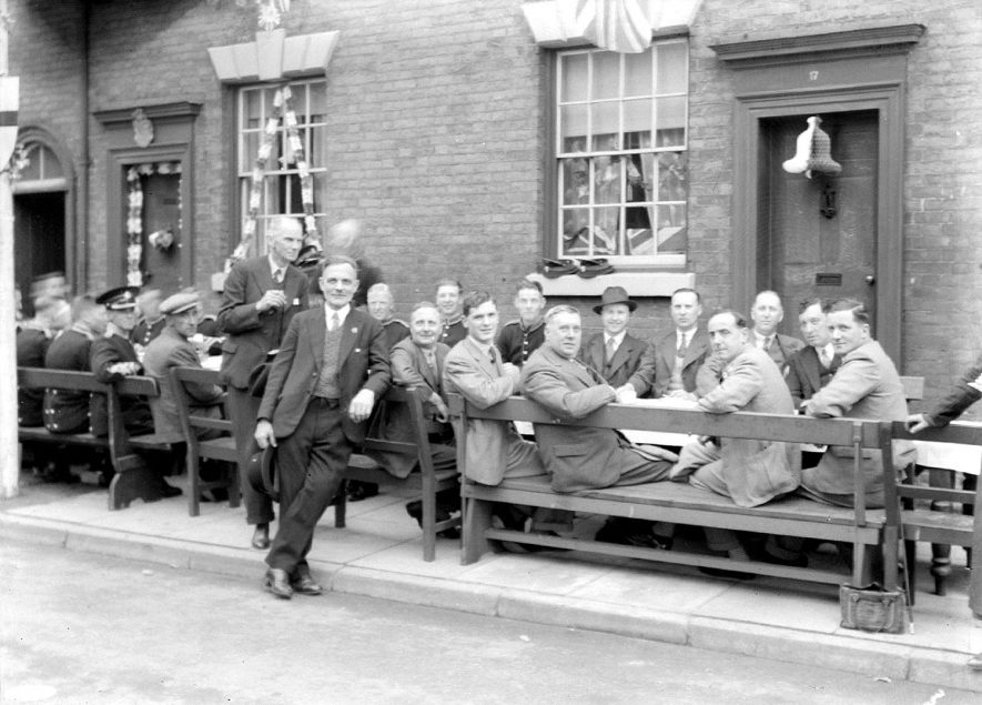 A street party in Alcester. A number of the men are wearing military? uniform.  1930s |  IMAGE LOCATION: (Warwickshire County Record Office)
