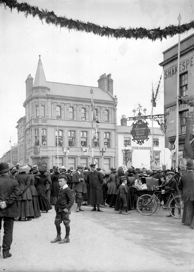 Celebration in Stratford upon Avon High Street, with a large crowd of people,  reason unknown.  1910s |  IMAGE LOCATION: (Warwickshire County Record Office)