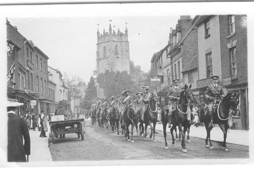 Military parade of soldiers and horses in Alcester High Street with the church in the background.  1900s |  IMAGE LOCATION: (Warwickshire County Record Office)