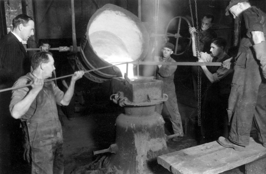 Workers pouring molten metal into a cast for a new church bell at Salford Priors.  1940s |  IMAGE LOCATION: (Warwickshire County Record Office)