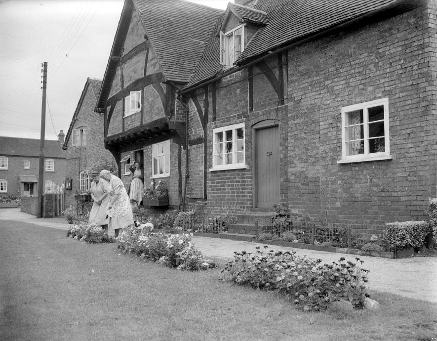 Bretford, best kept village. Mrs F.A. White, Mrs E.A. Cooper and Mrs I.E. Halfpenny and flower beds outside the Old Oaks.  August 1958 |  IMAGE LOCATION: (Warwickshire County Record Office) PEOPLE IN PHOTO: White, Mrs F A, White as a surname, Halfpenny, Mrs I E, Halfpenny as a surname, Cooper, Mrs E A, Cooper as a surname