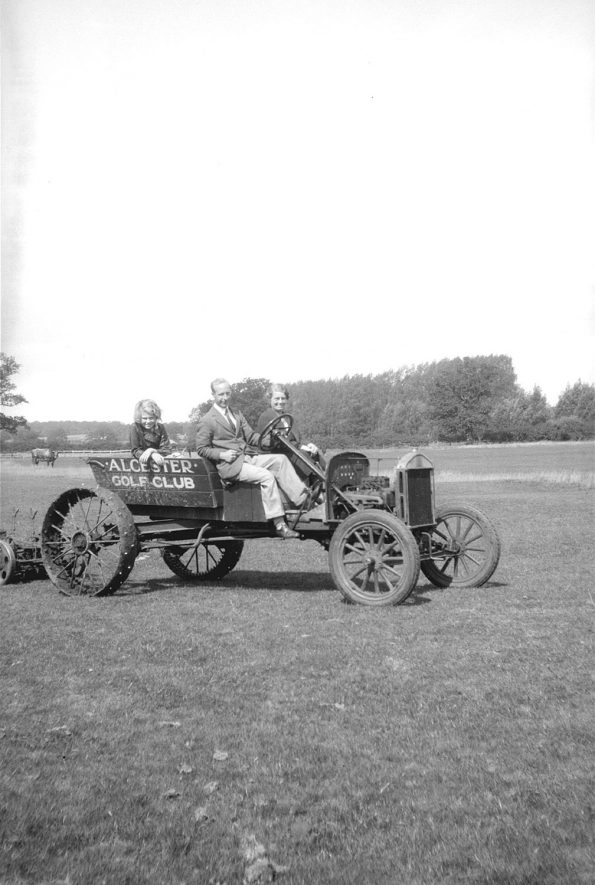 Grass-cutting vehicle on Alcester golf course. Two men and a girl riding on it.  1950s |  IMAGE LOCATION: (Warwickshire County Record Office)