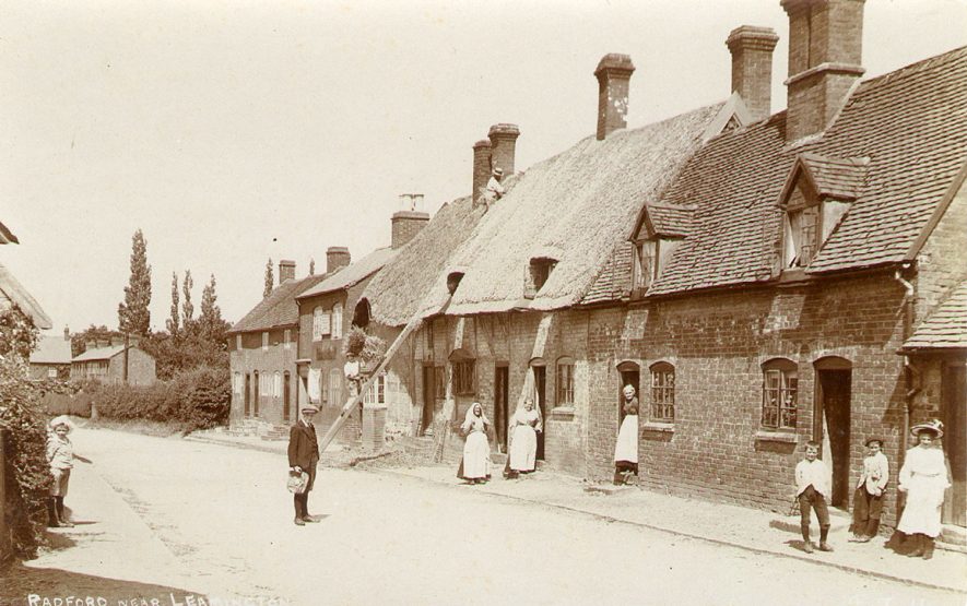 Village street with cottages, showing women and children and a thatcher at work, Radford Semele.  1900s |  IMAGE LOCATION: (Warwickshire County Record Office)