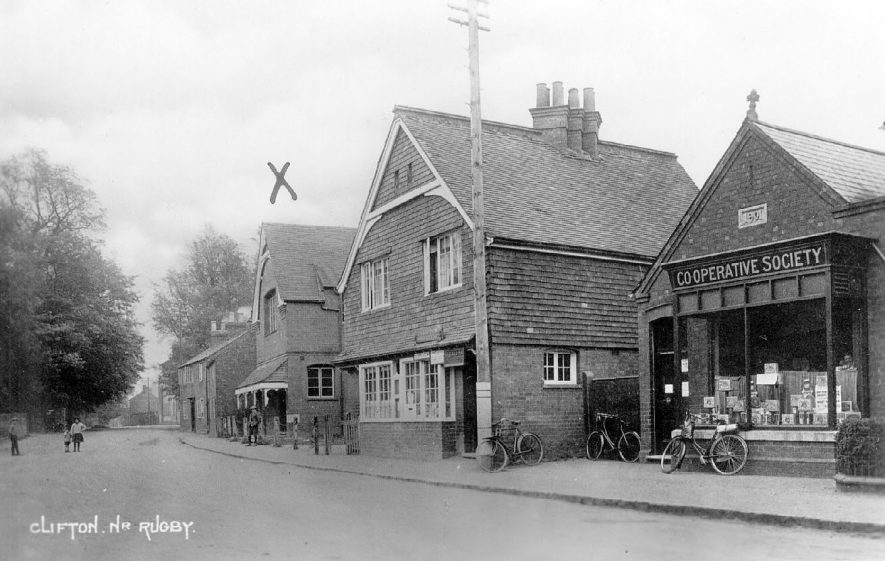Village street with the Village Hall, known as The Townsend Memorial Hall and Co-operative Stores with the post office between.  Clifton upon Dunsmore.  1930s |  IMAGE LOCATION: (Warwickshire County Record Office)