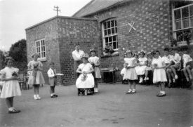 Group of children outside the school in Gaydon. They are dressed up possibly for May Day celebrations.  1959 |  IMAGE LOCATION: (Warwickshire County Record Office)