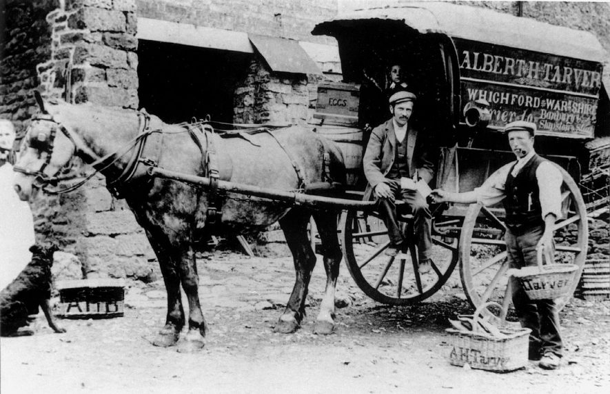 Two men with carriers cart labelled Albert H. Tarver, Whichford - Warwickshire, carrier to Banbury and Shipston on Stour, Cherington.  1900s |  IMAGE LOCATION: (Warwickshire County Record Office)