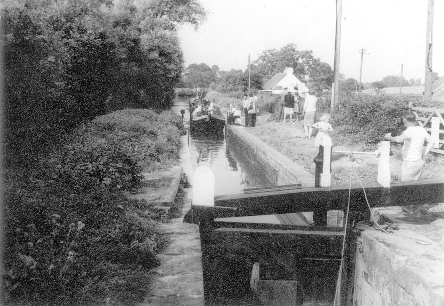 The Stratford upon Avon canal with a group of people watching a boat approaching a lock, Preston Bagot.  1964 |  IMAGE LOCATION: (Warwickshire County Record Office)