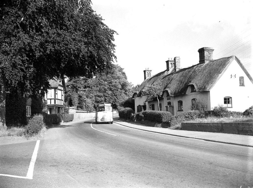 Village street showing junction of Leamington Road and Offchurch Lane, cottages and a bus, Radford Semele.  1956 |  IMAGE LOCATION: (Warwickshire County Record Office)