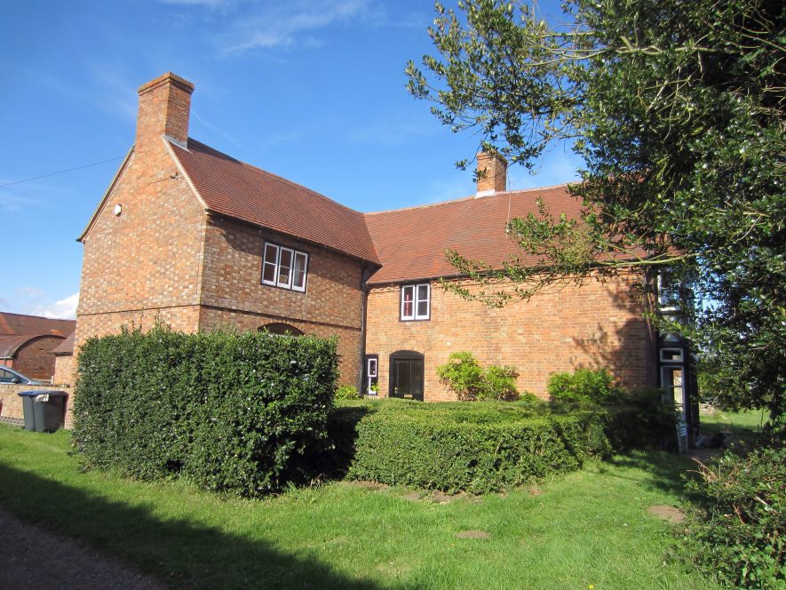 Lime Kiln Farm. Blue sky overhead with a tree to the right and a hedge in front. | Image courtesy of Anne Langley