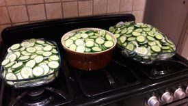 Sliced and salted cucumbers. Three large bowls stand on an oven range, full of cucumbers. | Image courtesy of Karen Moulder