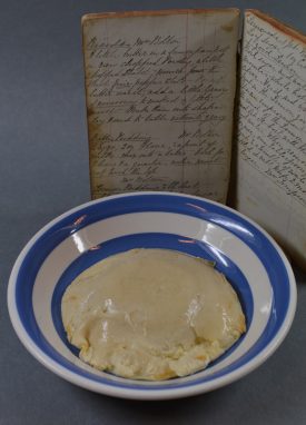 The batter pudding, and its recipe. The recipe stands behind a blue and white hooped bowl, which has the pudding (in off-white and slime) within. | Image courtesy of Robert Pitt, who did fine things with little material. Warwickshire County Record Office reference CR4817/1