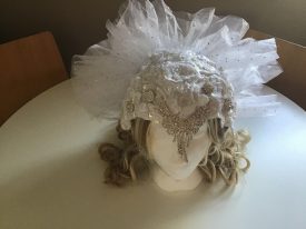 One of Sassi's fabulous headdresses. A white, beaded headdress over a blond wig with a net fanned out across the back | Image courtesy of Healey Moyes